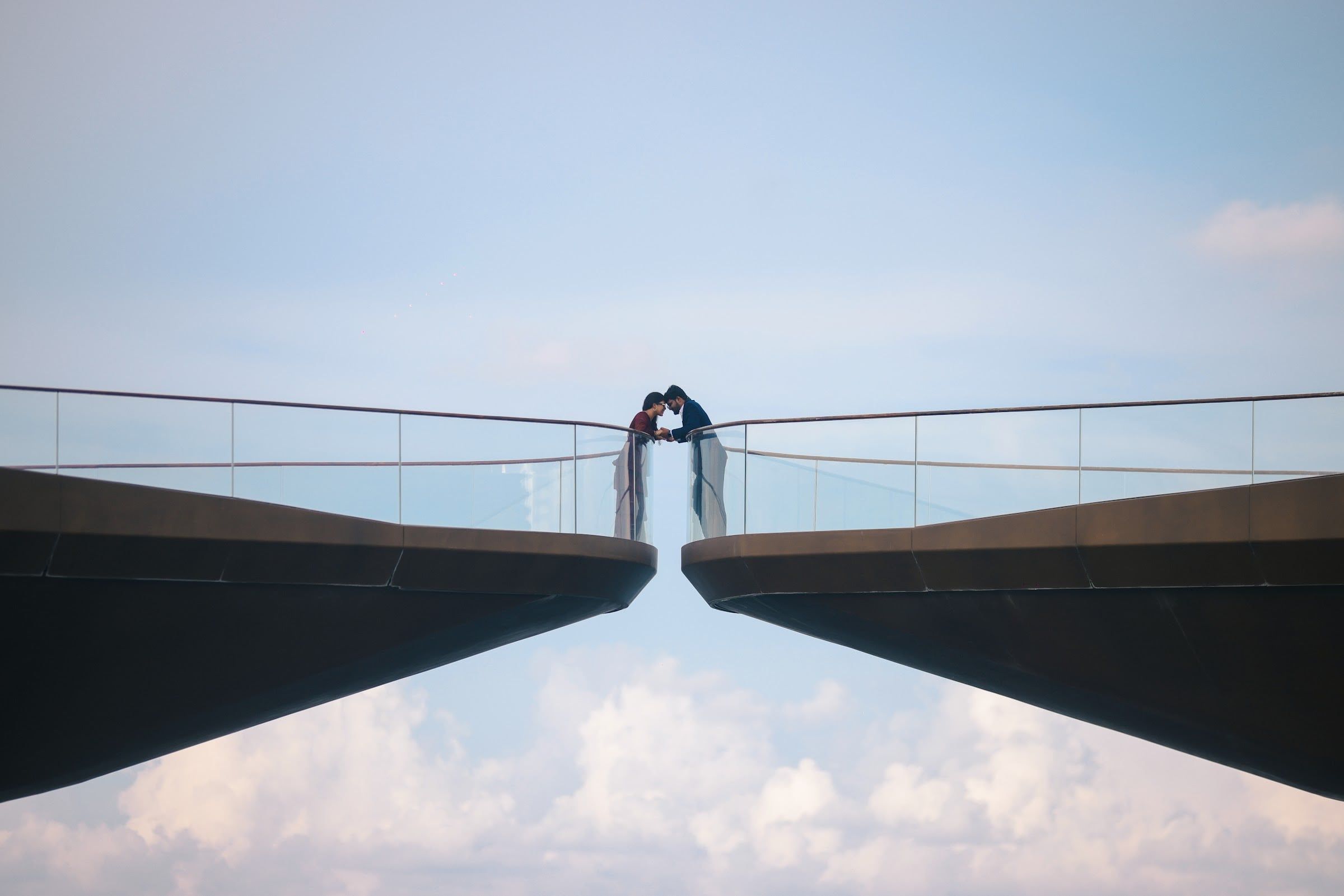 Couple kissing where two skybridges meet against the clouds