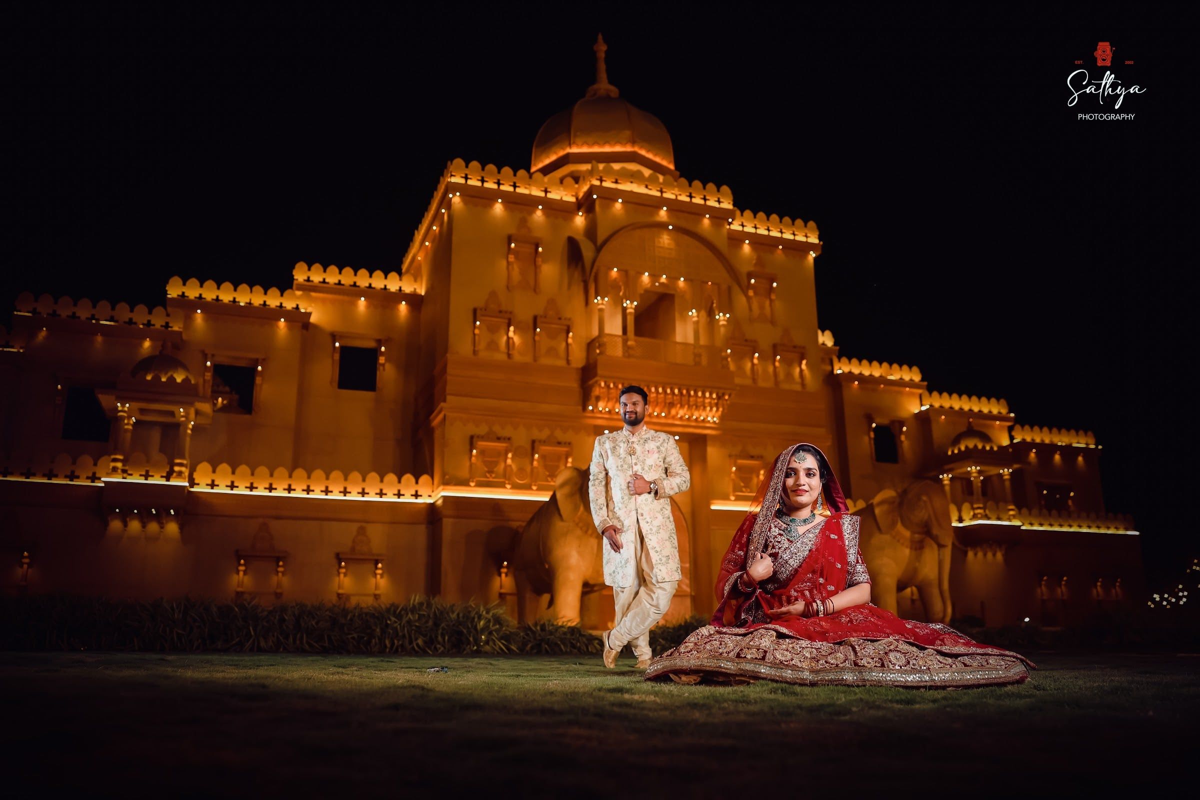 Bride and groom before a palace facade glowing at night