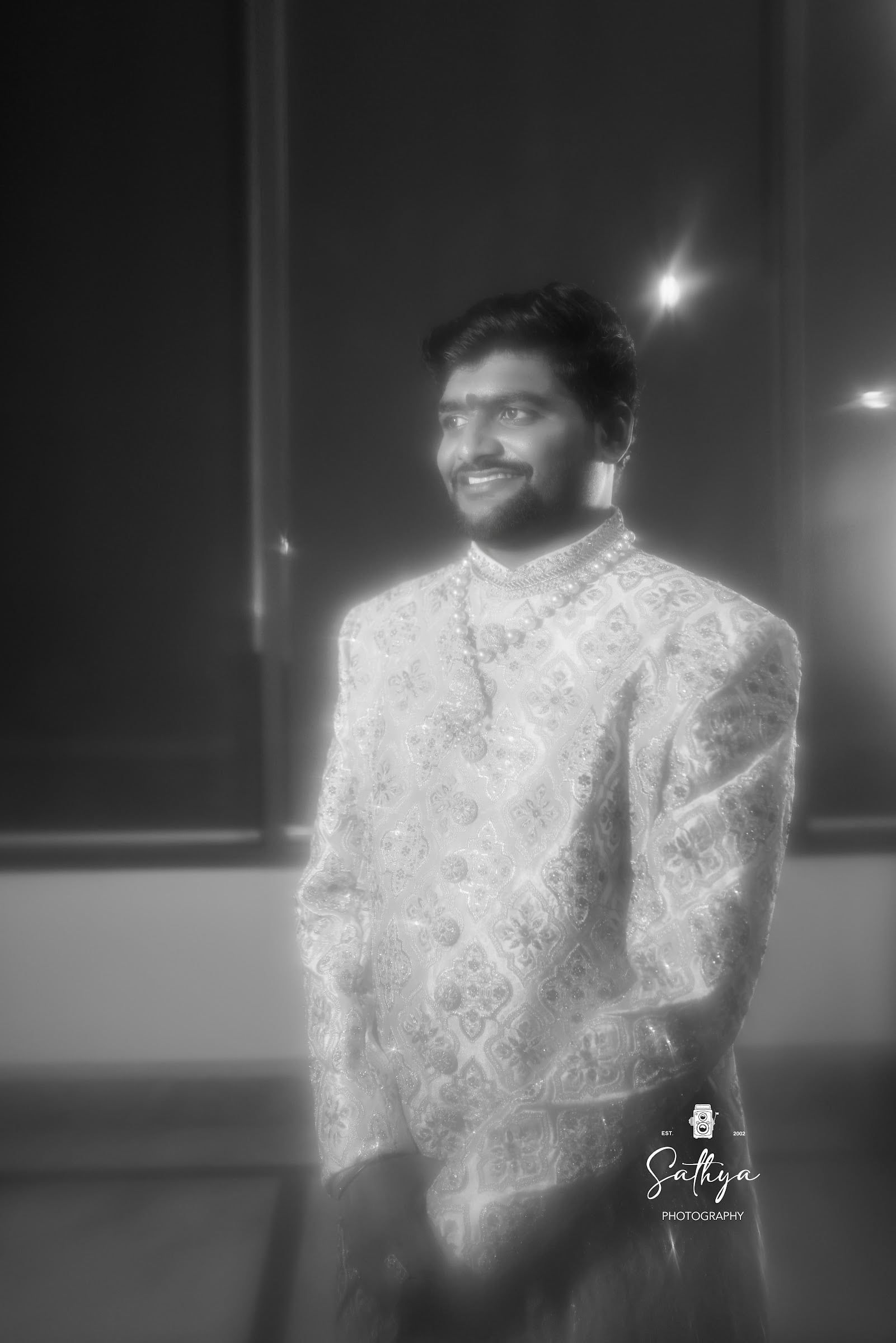 Black-and-white portrait of a smiling groom in a sherwani
