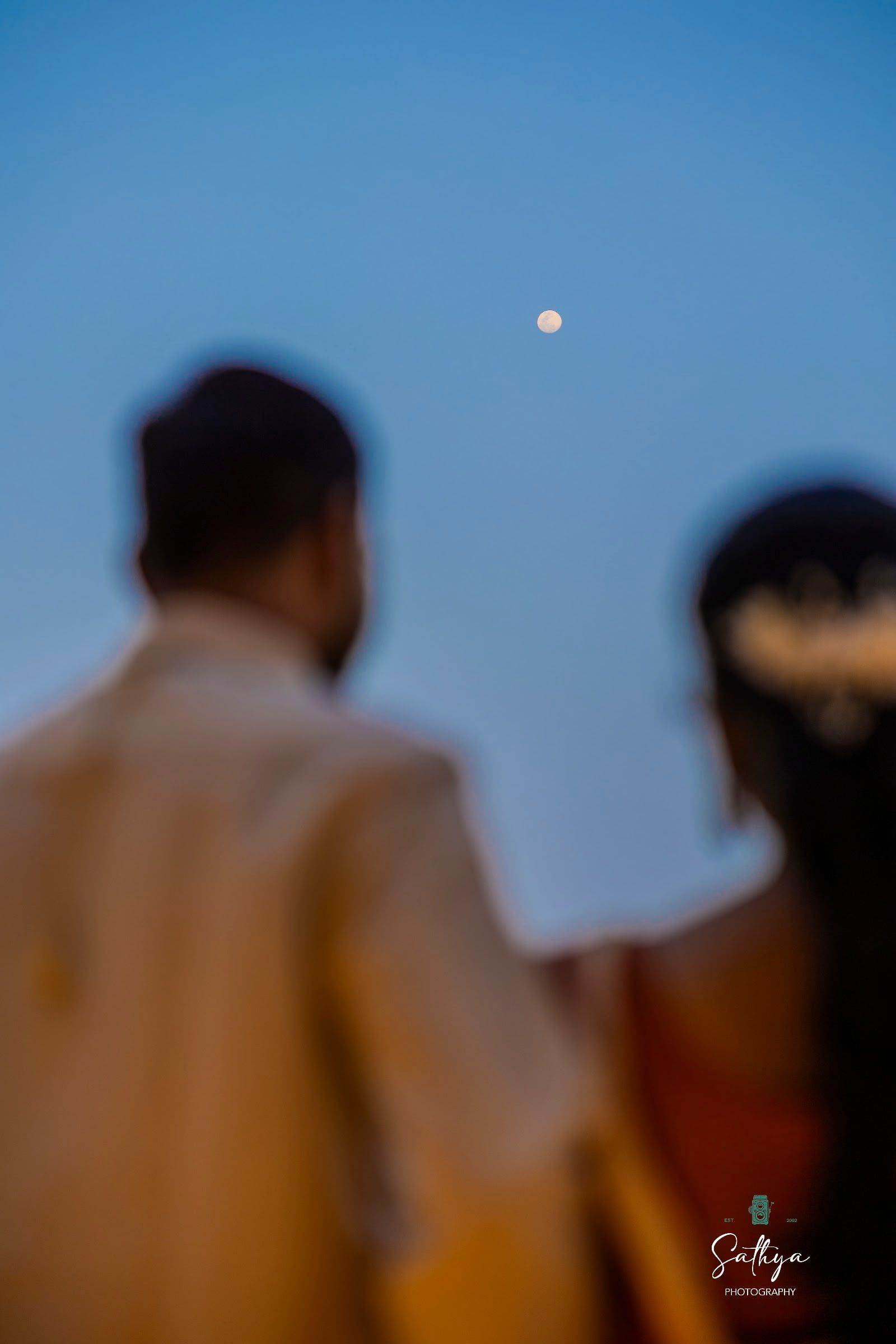 Couple looking toward a rising moon at dusk