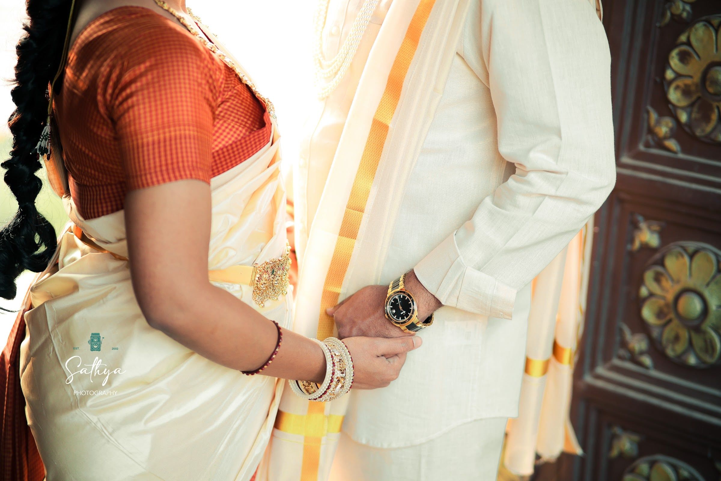 Detail of a pattu saree, bangles and the groom’s hand