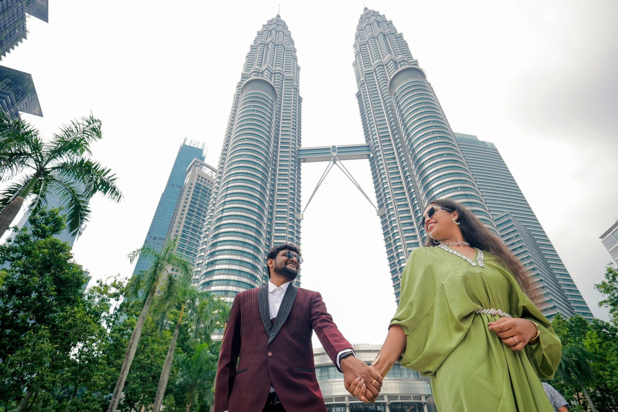 Couple holding hands beneath the Petronas Towers