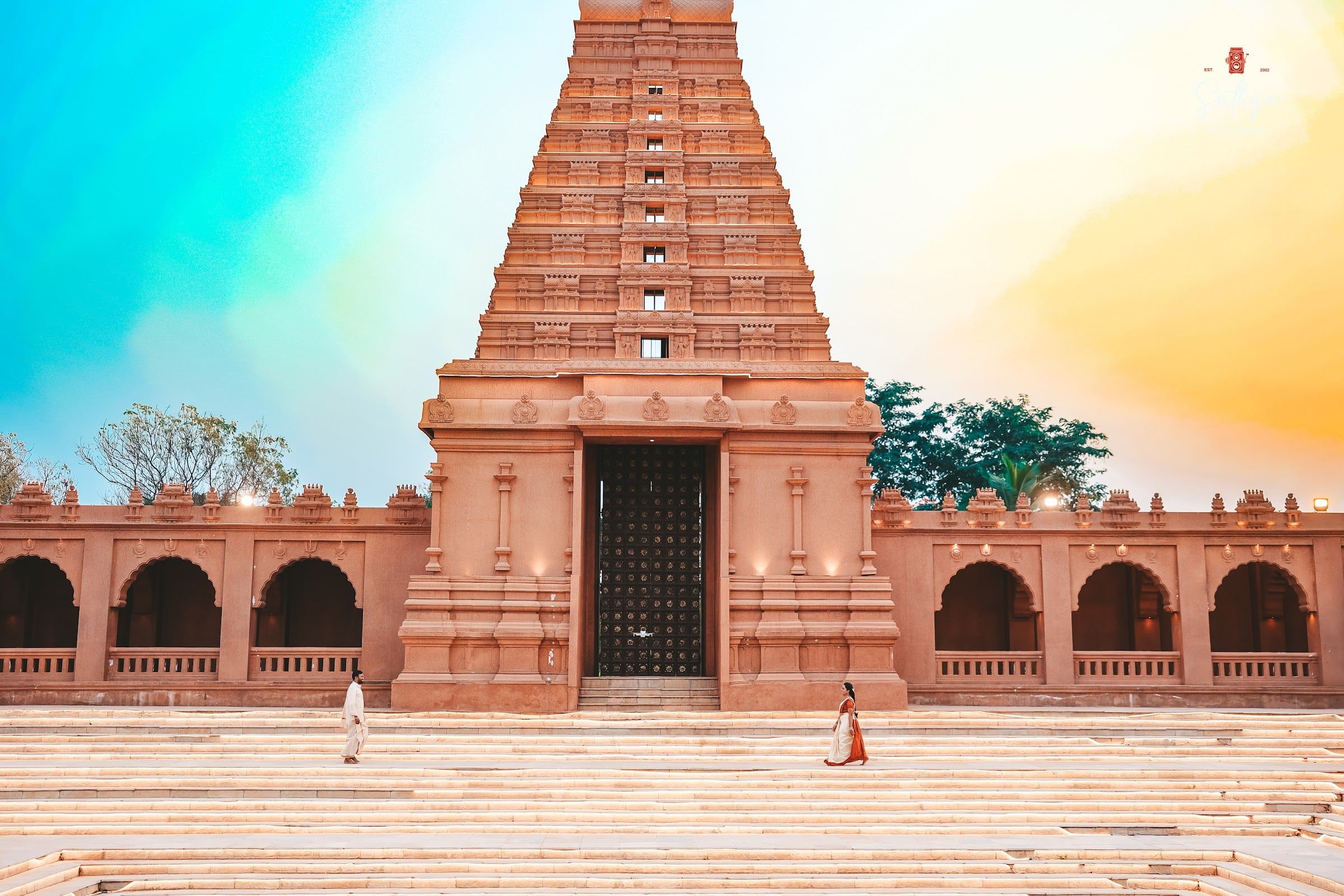 Wide frame of a couple walking before a temple gopuram