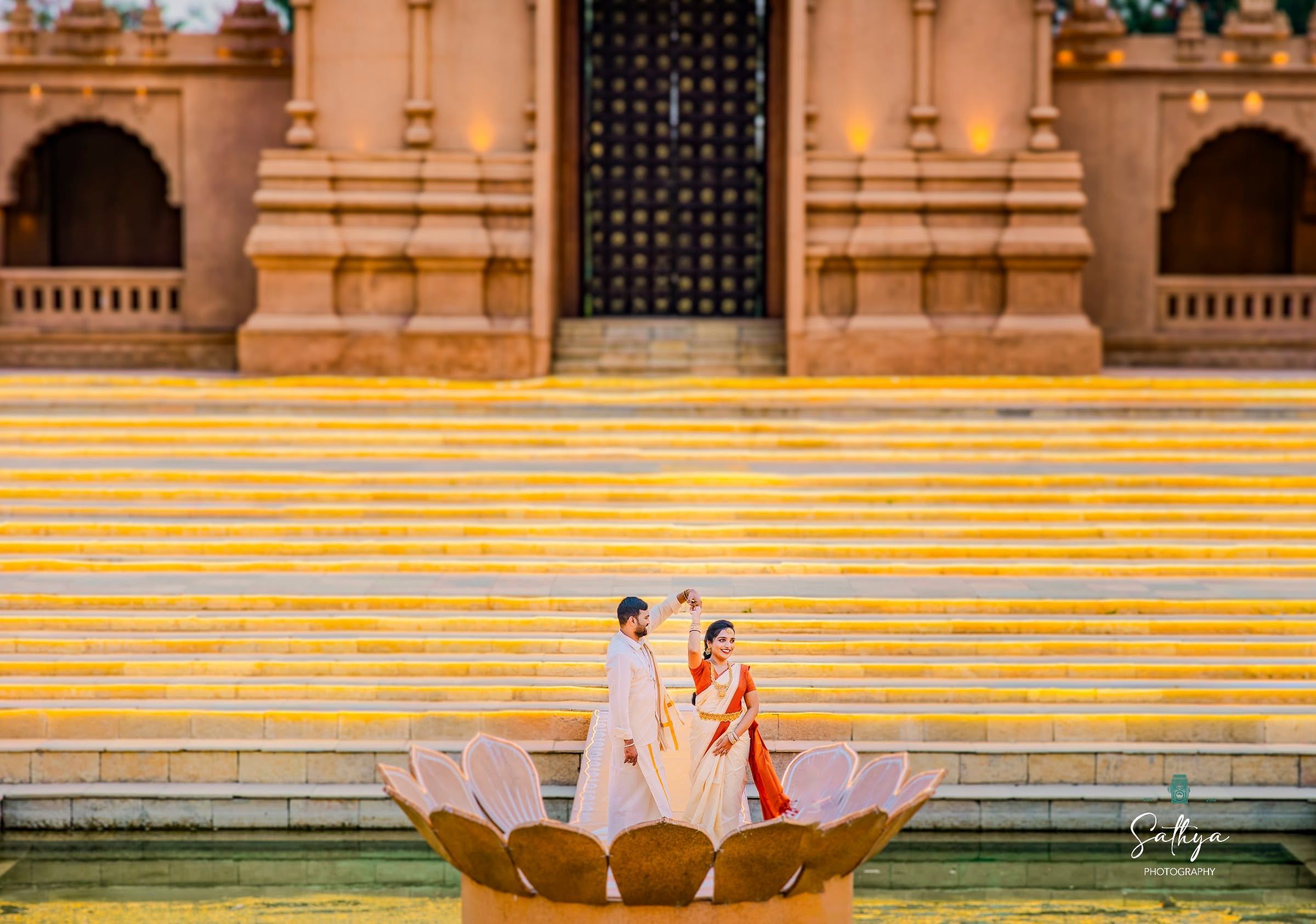 Couple dancing on golden temple steps beside a stone lotus