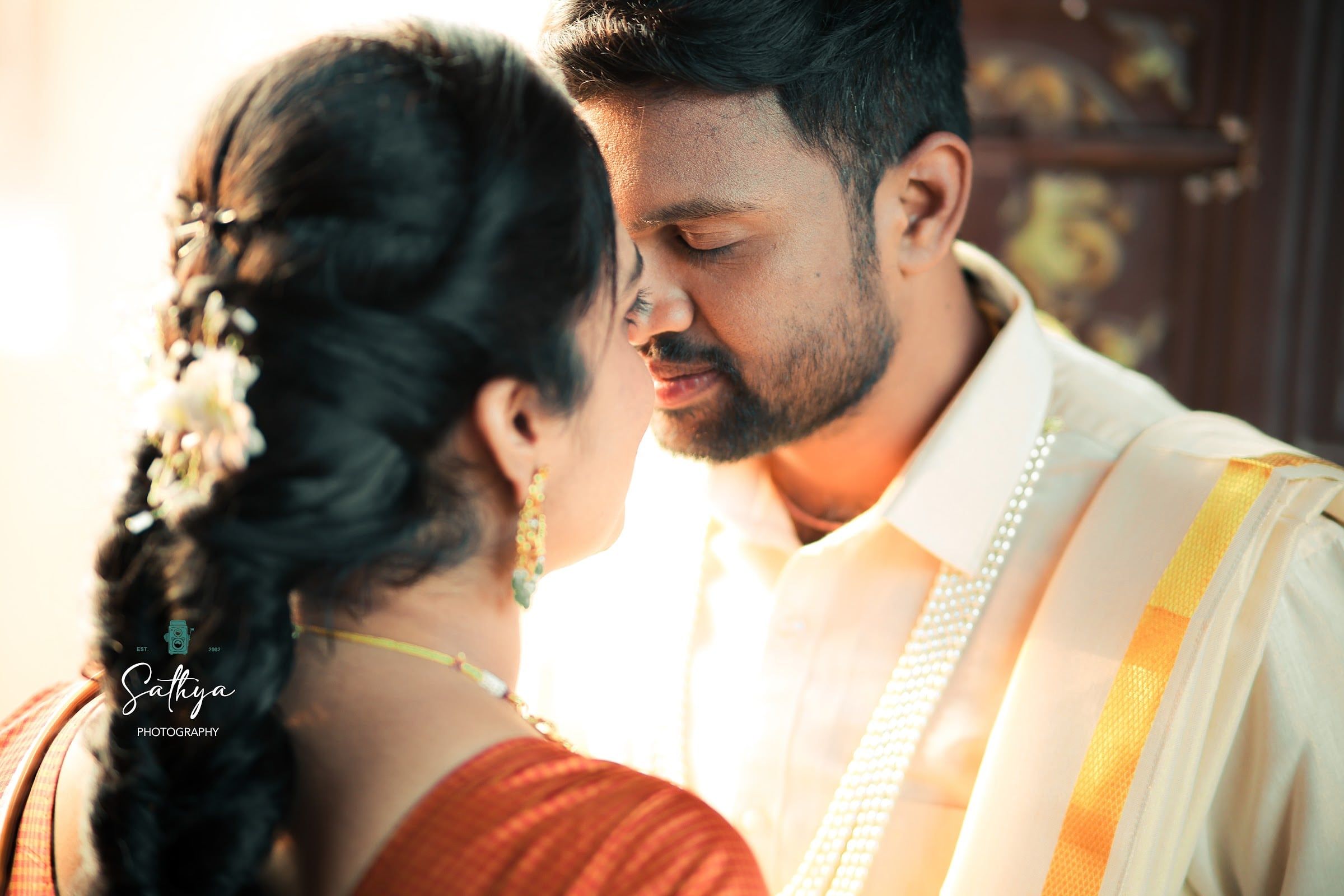 Tender close-up of a couple in a cream and gold kasavu saree