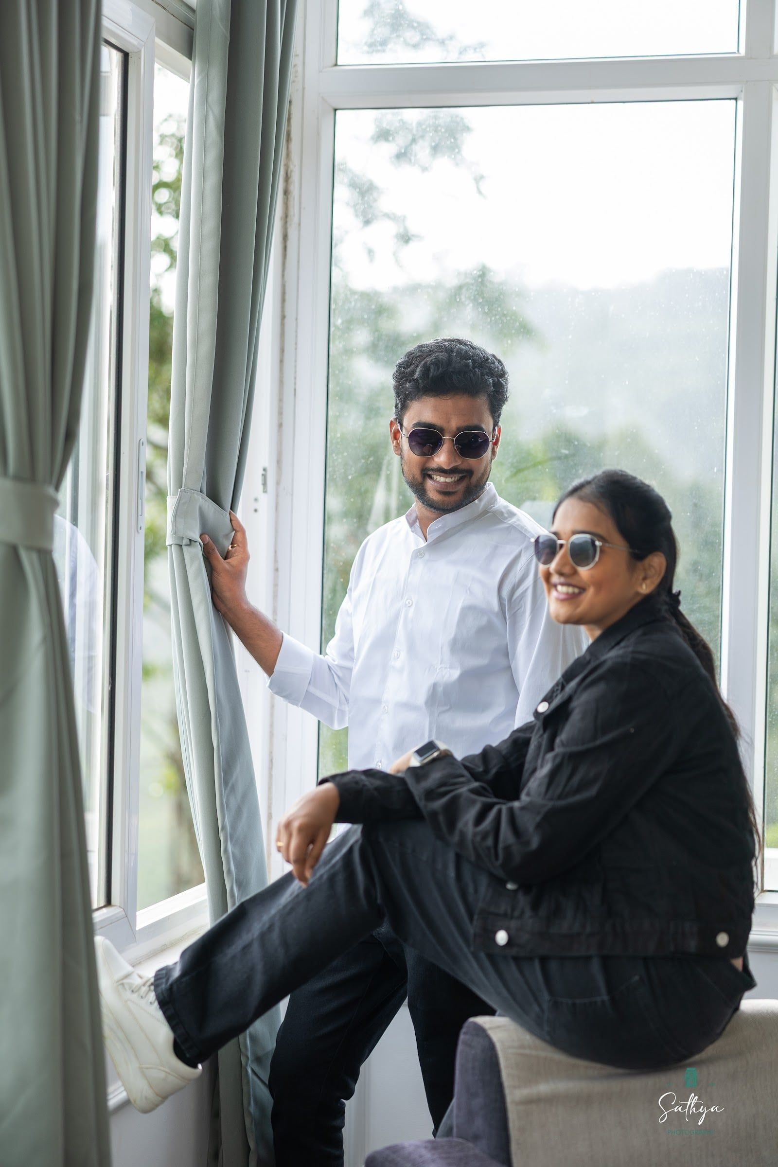 Couple laughing by a tall window in soft hill-station light